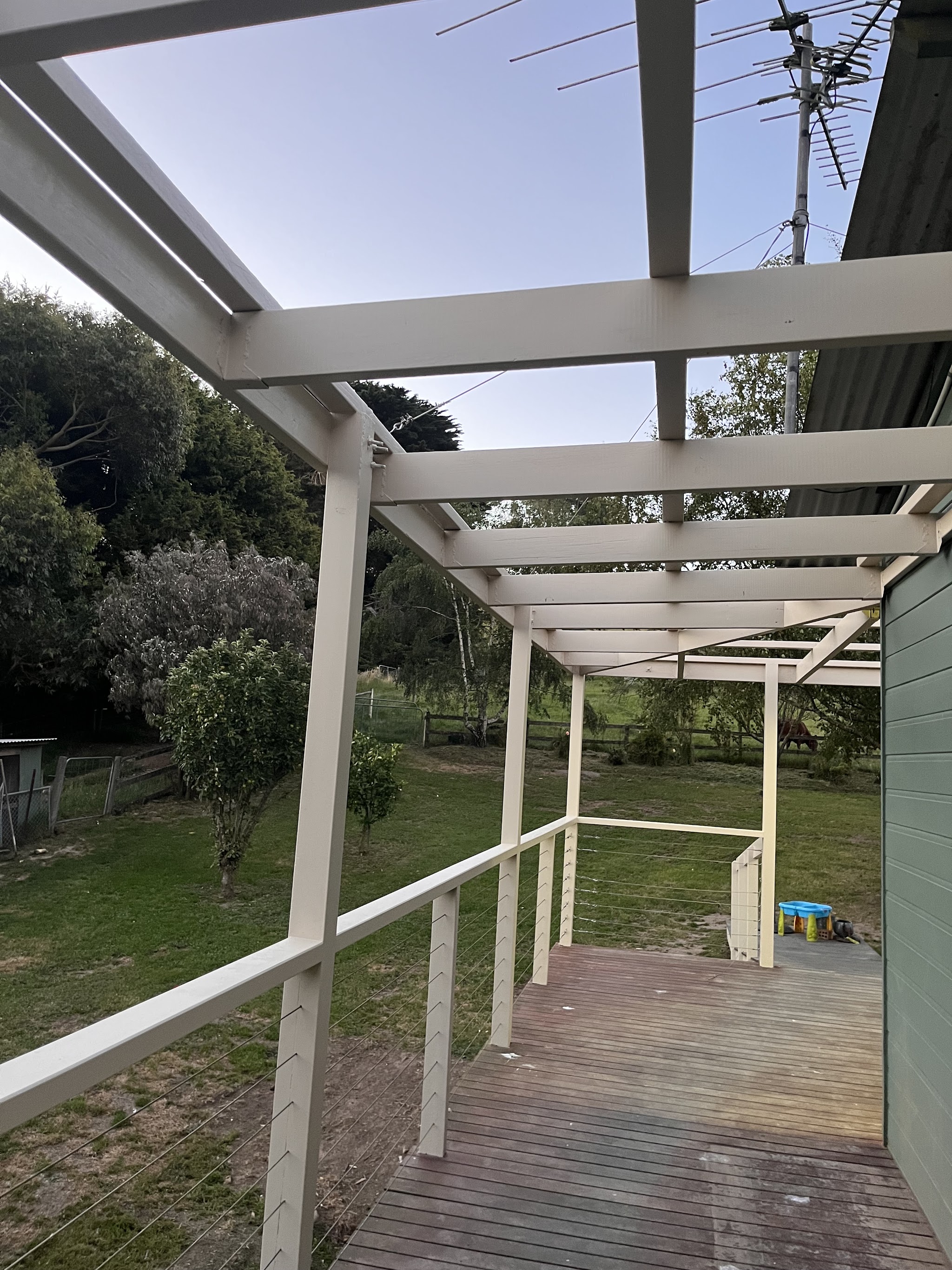 A white painted pergola over a timber deck looking out over paddocks