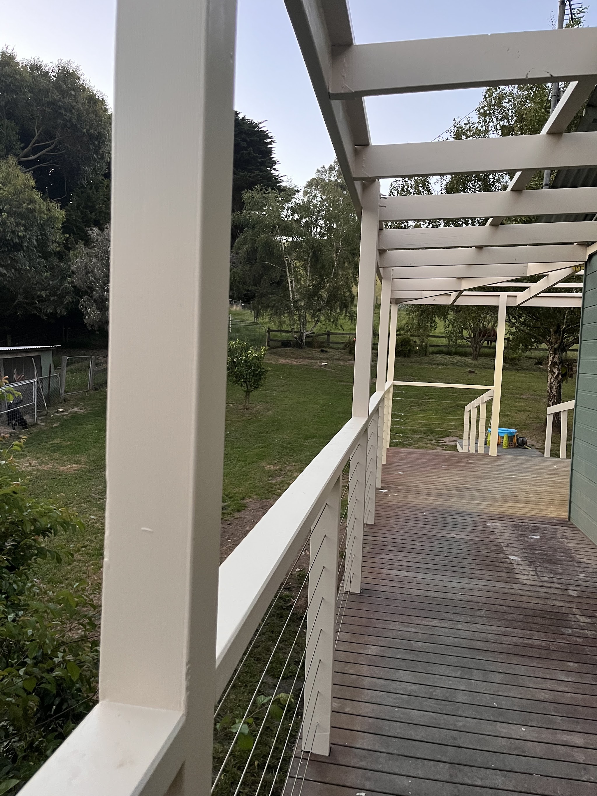 White painted pergola over a timber deck looking out to paddocks